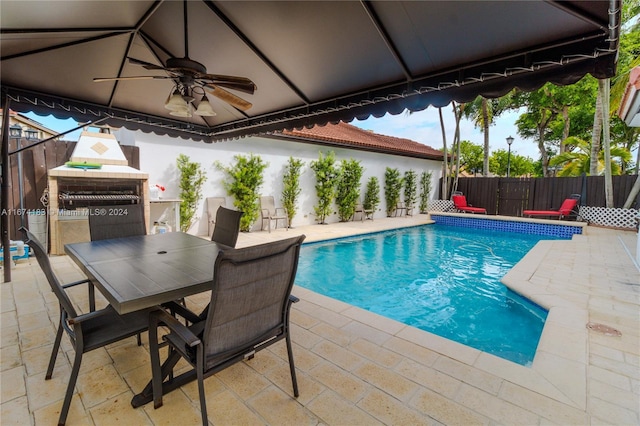 view of swimming pool featuring outdoor dining space, fence, a patio, and a ceiling fan