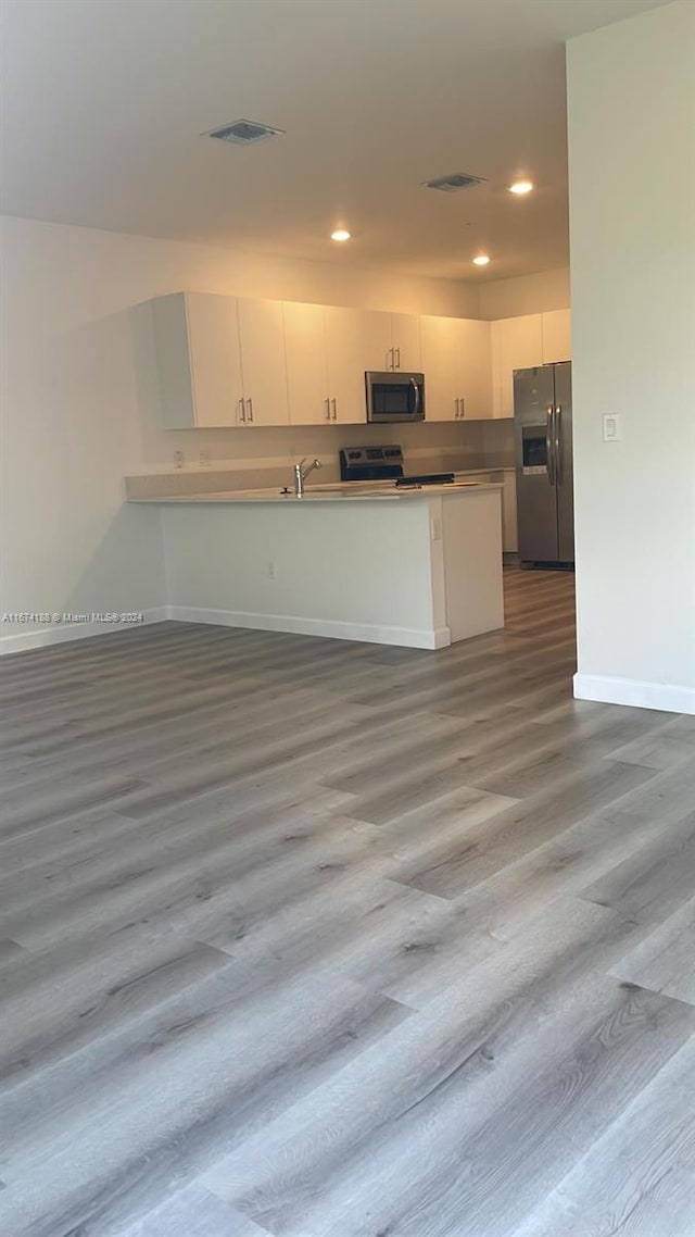 kitchen featuring white cabinets, sink, kitchen peninsula, dark wood-type flooring, and appliances with stainless steel finishes