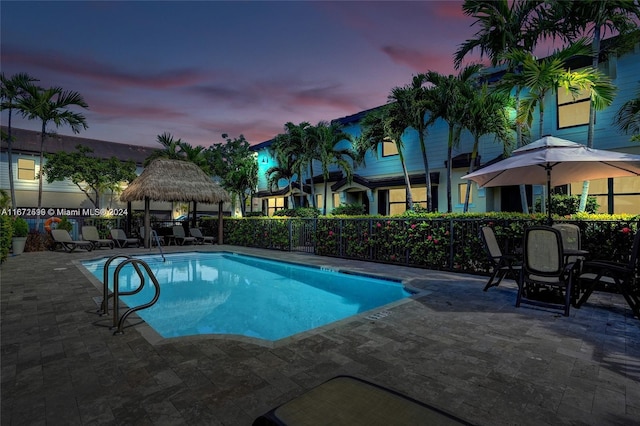 pool at dusk with a gazebo and a patio