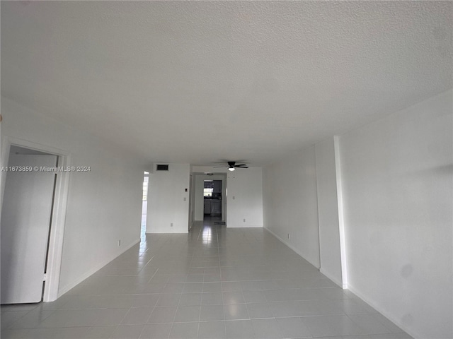 tiled empty room featuring a textured ceiling and ceiling fan