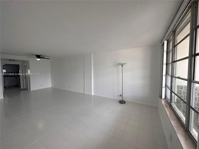 unfurnished room featuring ceiling fan, light tile patterned floors, and a textured ceiling