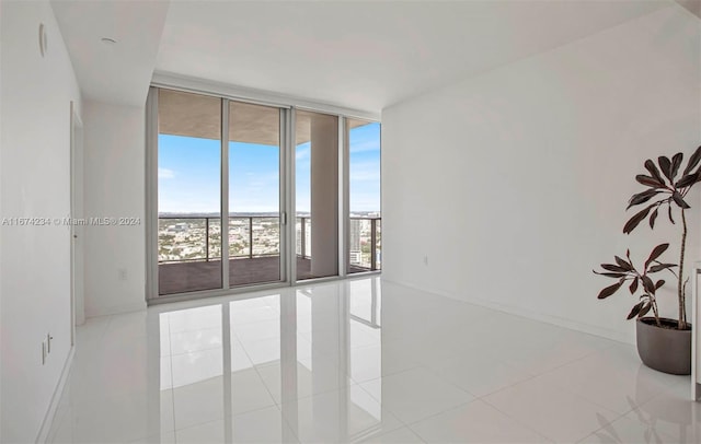 empty room featuring a wall of windows and light tile patterned floors