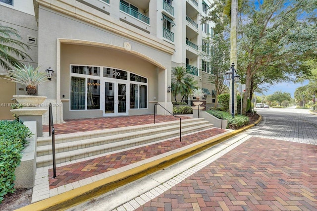 view of exterior entry with a balcony and french doors