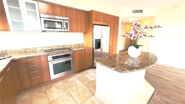 kitchen featuring a center island, stainless steel appliances, stone counters, and light tile patterned floors