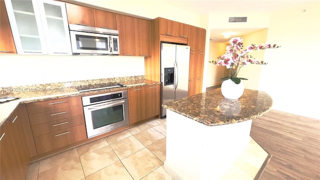 510 NW 84th Ave Unit 529, Plantation, FL 33324 - kitchen with appliances with stainless steel finishes, dark stone counters, brown cabinets, glass insert cabinets, and a kitchen island