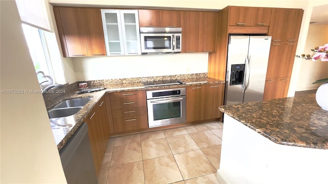 kitchen with sink, light tile patterned flooring, stainless steel appliances, and dark stone counters