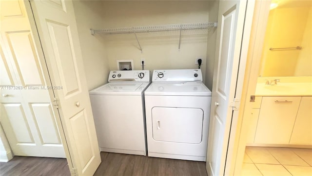 laundry area featuring sink, wood-type flooring, and washer and clothes dryer