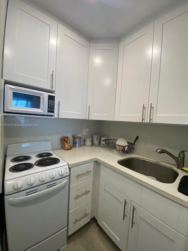 kitchen with light stone counters, white appliances, sink, and white cabinets