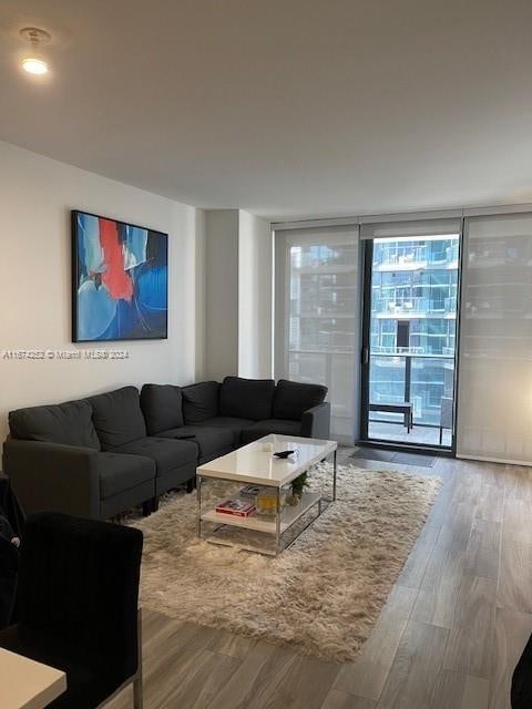 living room with wood-type flooring and floor to ceiling windows