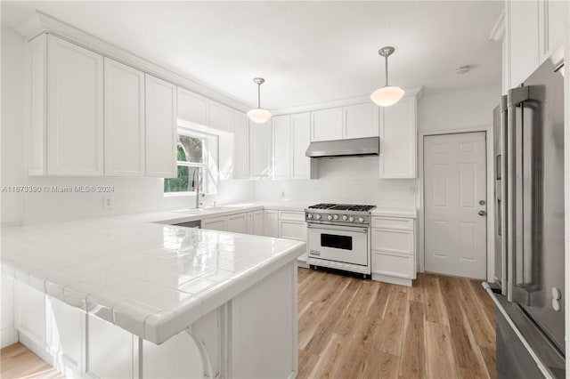 kitchen featuring high quality appliances, kitchen peninsula, decorative light fixtures, light hardwood / wood-style floors, and white cabinetry