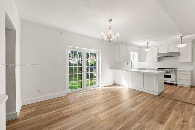 kitchen with white cabinets, high end stainless steel range oven, hanging light fixtures, light wood-type flooring, and kitchen peninsula