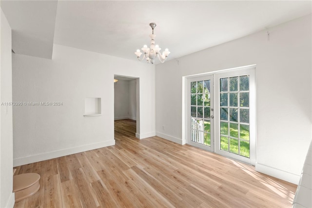 empty room with light hardwood / wood-style floors and a notable chandelier