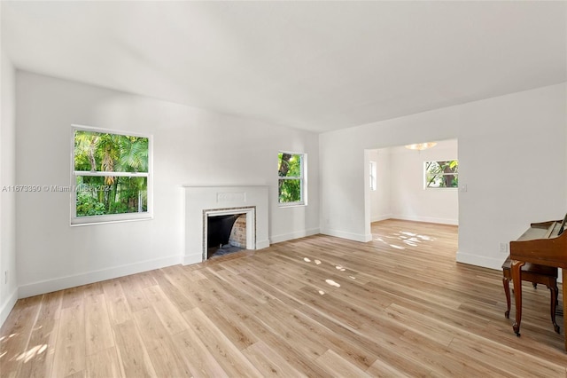 unfurnished living room with a fireplace, a healthy amount of sunlight, and light hardwood / wood-style floors