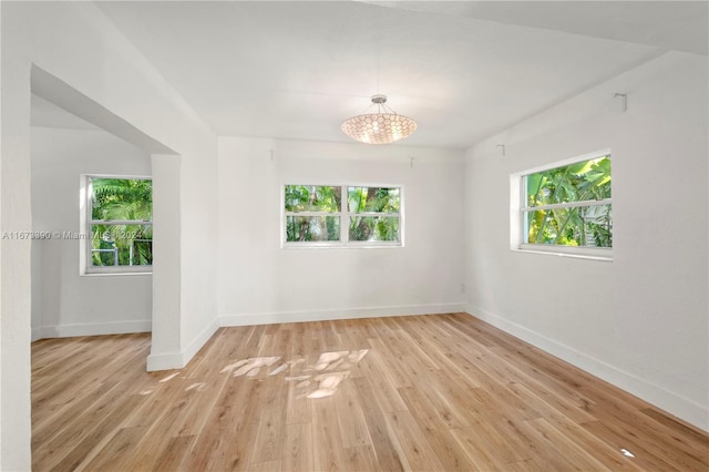 unfurnished room featuring light wood-type flooring and a notable chandelier