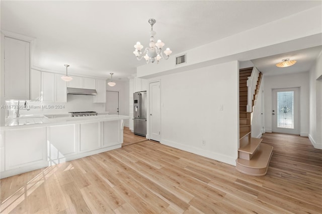 kitchen with pendant lighting, white cabinets, sink, light wood-type flooring, and stainless steel appliances