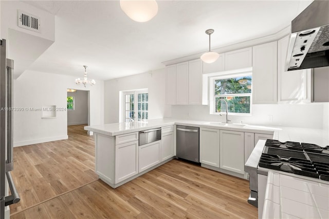 kitchen with kitchen peninsula, a wealth of natural light, stainless steel appliances, exhaust hood, and pendant lighting