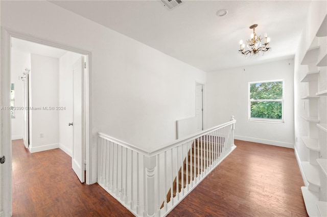 hallway with an inviting chandelier and dark wood-type flooring