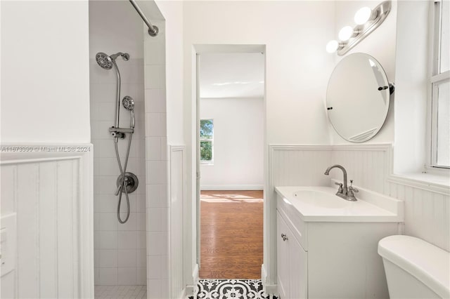 bathroom featuring a tile shower, vanity, hardwood / wood-style flooring, and toilet