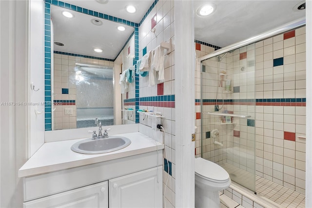 full bath with vanity, toilet, tile walls, and a shower stall