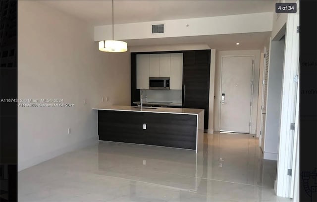 kitchen featuring pendant lighting, white cabinets, and sink