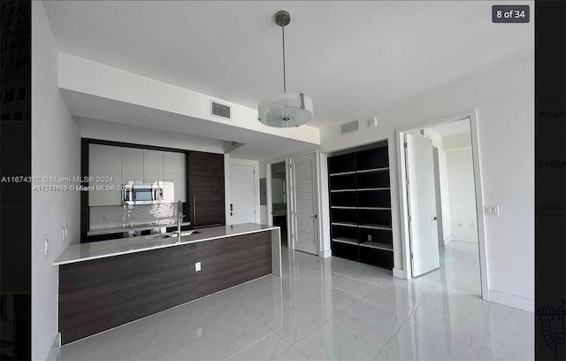 kitchen featuring dark brown cabinets, hanging light fixtures, and sink