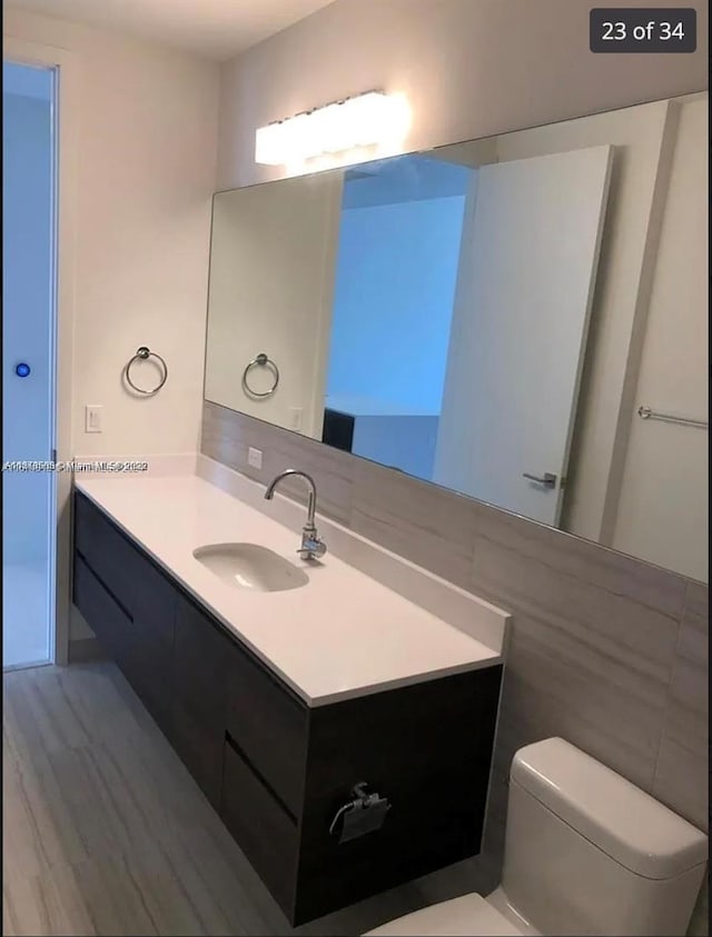 bathroom with hardwood / wood-style floors, vanity, and toilet