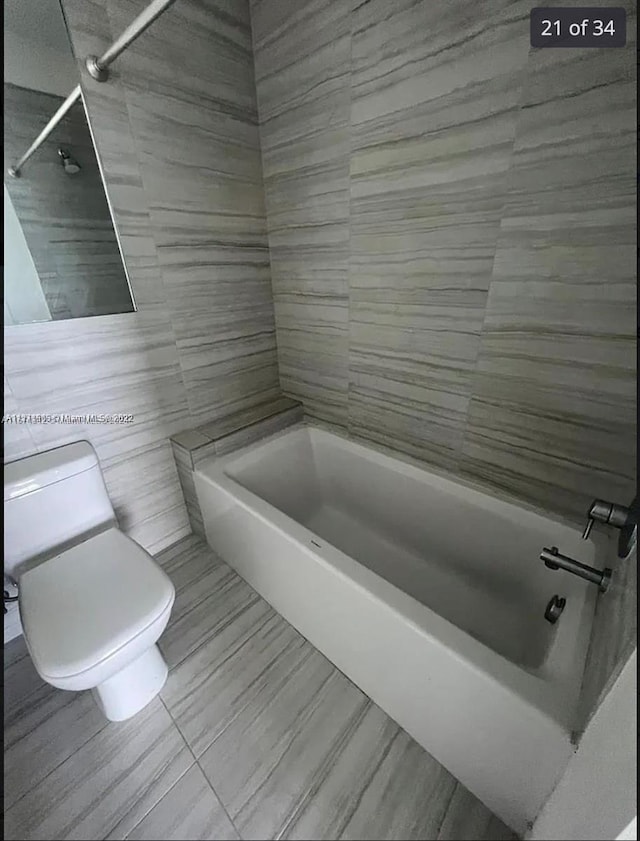 bathroom featuring shower / bathing tub combination, tile walls, and toilet