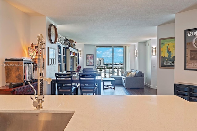 dining room featuring a textured ceiling, a wall of windows, wood finished floors, and baseboards