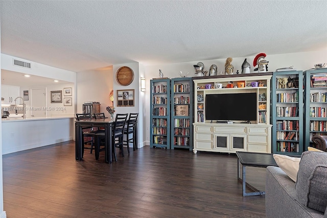 living area featuring a textured ceiling, wood finished floors, visible vents, and baseboards