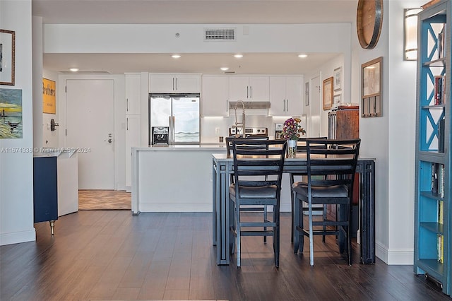 kitchen with appliances with stainless steel finishes, white cabinets, visible vents, and dark wood-style floors