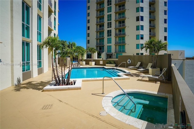 pool with a patio area and a hot tub