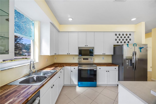 kitchen with white cabinets, appliances with stainless steel finishes, sink, and wood counters