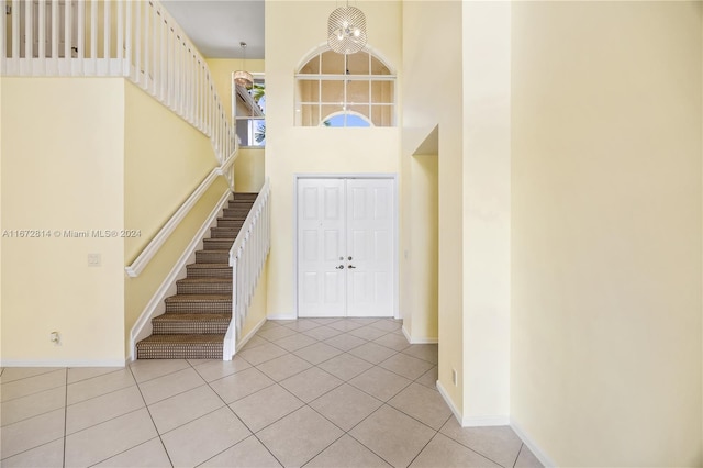 foyer entrance featuring a towering ceiling, a chandelier, and light tile patterned floors