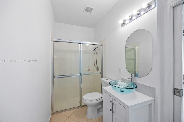 bathroom with tile patterned flooring, a shower with door, vanity, and toilet