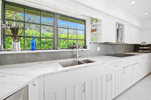 kitchen with light stone countertops, sink, backsplash, black electric cooktop, and white cabinets