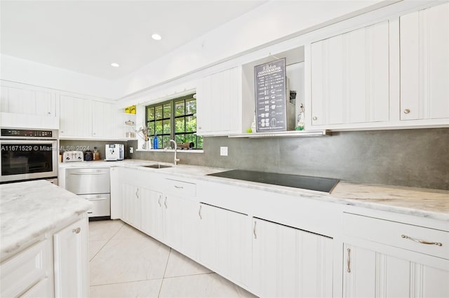 kitchen featuring oven, black electric stovetop, white cabinetry, and sink