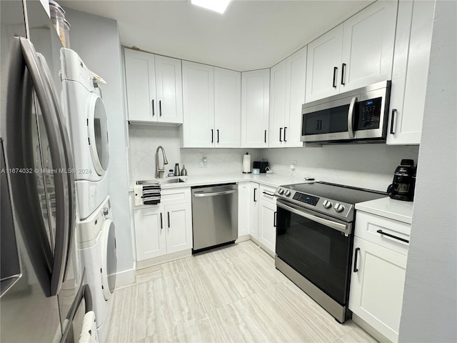 kitchen with stacked washer and dryer, backsplash, sink, white cabinetry, and appliances with stainless steel finishes