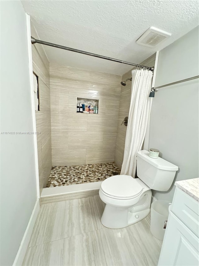 bathroom with vanity, curtained shower, a textured ceiling, and toilet