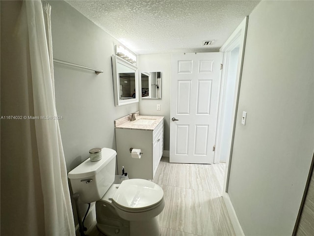 bathroom with vanity, a textured ceiling, toilet, and tile patterned floors