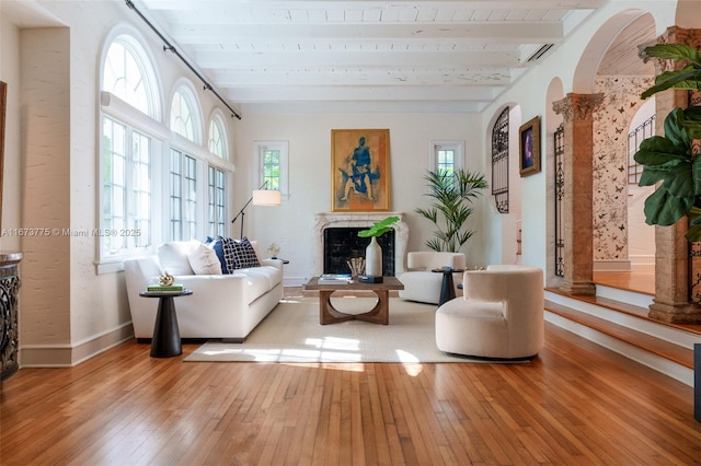 living area featuring beam ceiling, light hardwood / wood-style flooring, and wooden ceiling