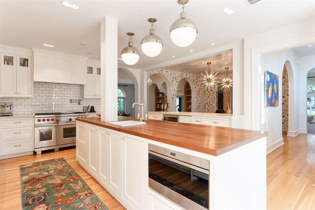 kitchen featuring sink, white cabinets, and range with two ovens