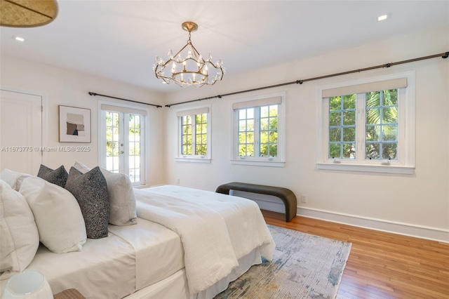 bedroom with a chandelier, french doors, light hardwood / wood-style floors, and multiple windows