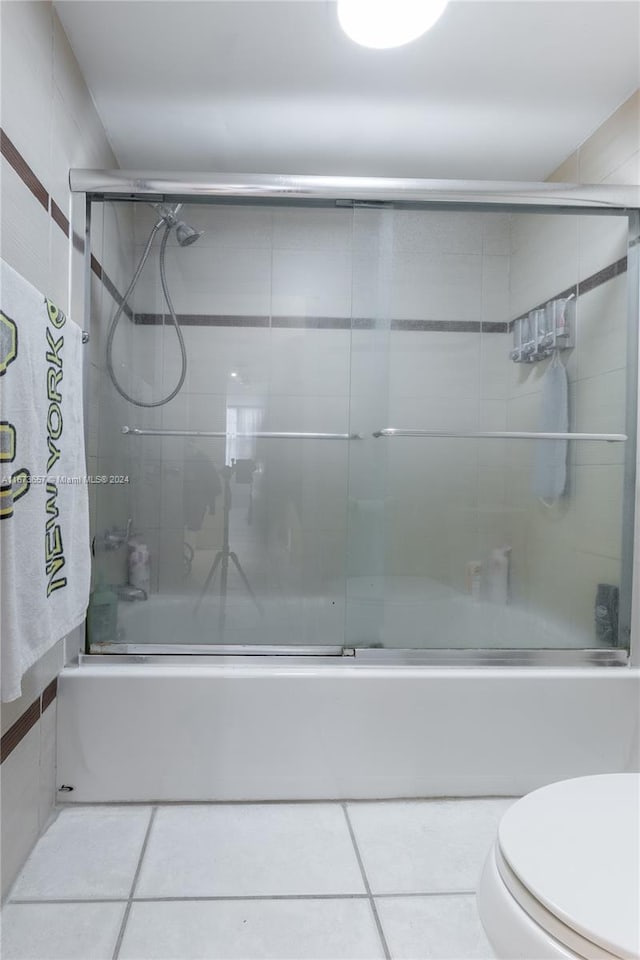 bathroom featuring bath / shower combo with glass door, tile patterned floors, and toilet