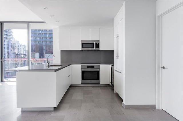 kitchen with stainless steel appliances, kitchen peninsula, sink, and white cabinetry