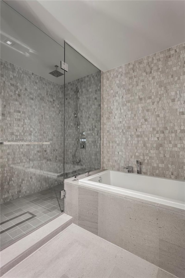 bathroom featuring plus walk in shower and tile walls