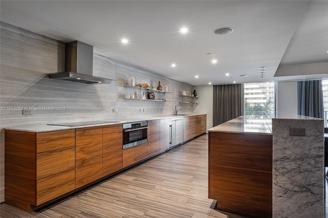 kitchen featuring black electric cooktop, light stone counters, oven, tasteful backsplash, and wall chimney exhaust hood