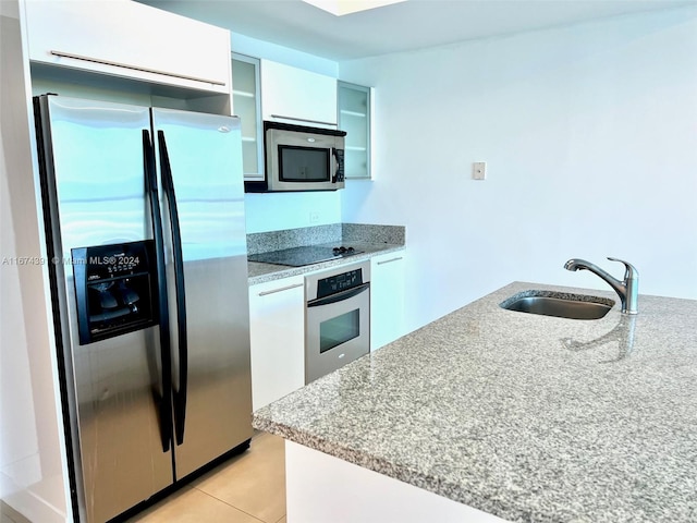 kitchen with sink, light stone counters, white cabinets, appliances with stainless steel finishes, and light tile patterned floors