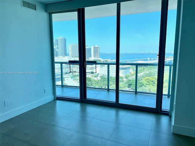 tiled spare room with a water view and expansive windows