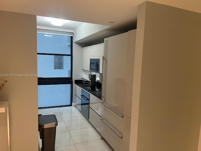 kitchen with white cabinets, black appliances, and light tile patterned floors