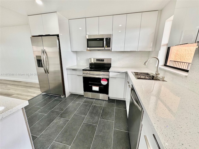 kitchen featuring appliances with stainless steel finishes, light stone countertops, sink, and white cabinets